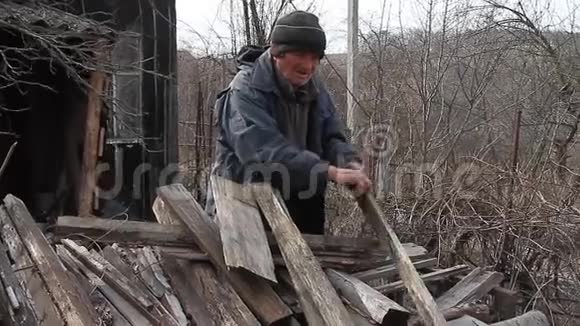 一个非常老的人通过木板来修理小屋或点燃火战后的生活视频的预览图