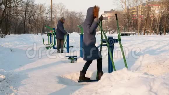 穿着蓝色夹克的男人和女人在冬季公园里从事模拟器侧视视频的预览图