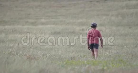 一个戴帽子的男孩正沿着山坡走大风在吹视频的预览图
