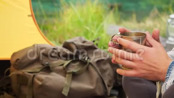 男人手里拿着铁杯在野外的旅行帐篷里视频的预览图