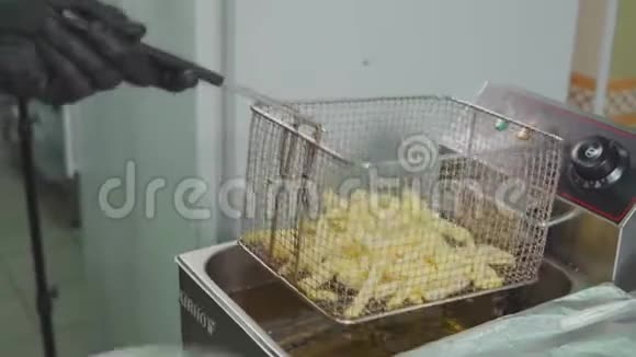 烹饪工人正在用电油炸锅把土豆片放入沸水中视频的预览图