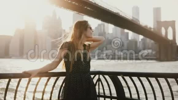 美丽的白种人年轻女子头发随风飘动在令人惊叹的日落河码头拍照纽约4K视频的预览图