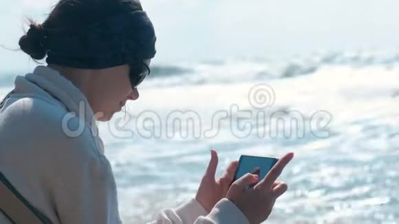 女人拍摄坐在岸上的大海和海浪视频的预览图