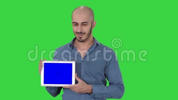 微笑休闲男子呈现一个平板电脑与空白屏幕上的绿色屏幕铬键视频的预览图