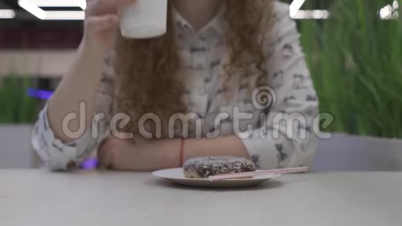 年轻漂亮的红发女人坐在咖啡馆里把一杯咖啡放在桌子上视频的预览图