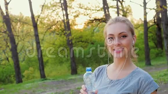 健身妇女从公园的瓶子里喝水视频的预览图