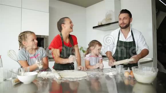 家庭有乐趣彼此玩面粉快乐的父母在围裙帮助孩子做饭视频的预览图
