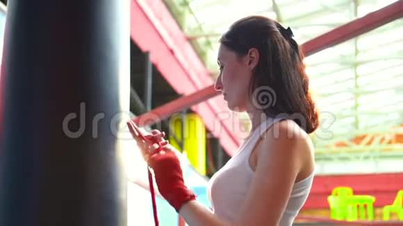 日落时分女人在一个时髦的健身房里用拳击胶带包住她的手把慢音乐合上视频的预览图