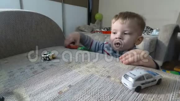 一个小男孩在扶手椅上玩他的玩具幼儿男孩在玩玩具汽车视频的预览图