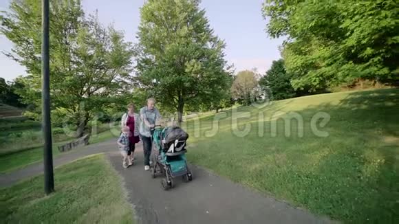 幸福的年轻家庭在外面的道路上行走绿色慢动作全高清视频的预览图