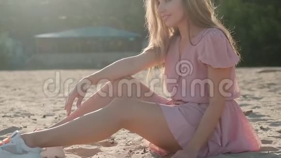 穿着夏装的少女坐在沙滩上微笑着视频的预览图