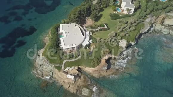 在透明的绿松石海岩石海岸环绕的海角上俯瞰幽静的别墅视频的预览图