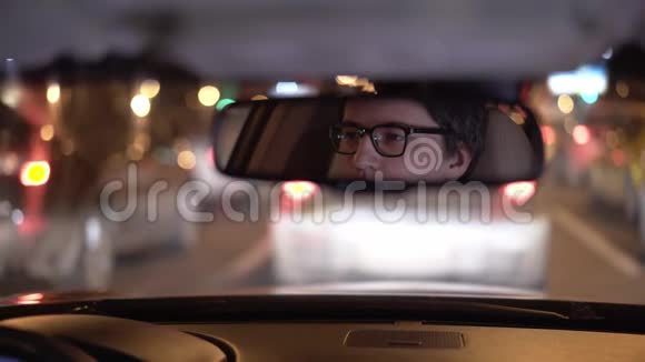 体贴的年轻商人的脸在后视镜里晚上开车视频的预览图