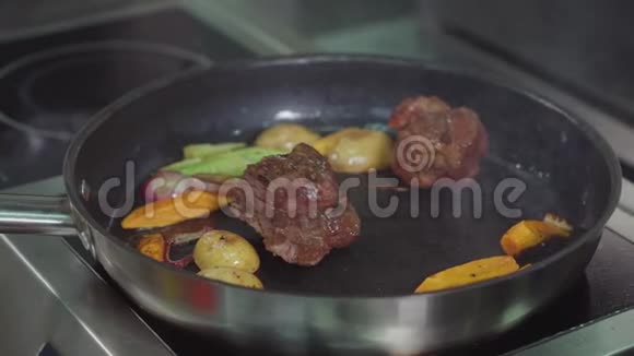 男人正用平底锅煎两块牛肉和蔬菜特写镜头视频的预览图