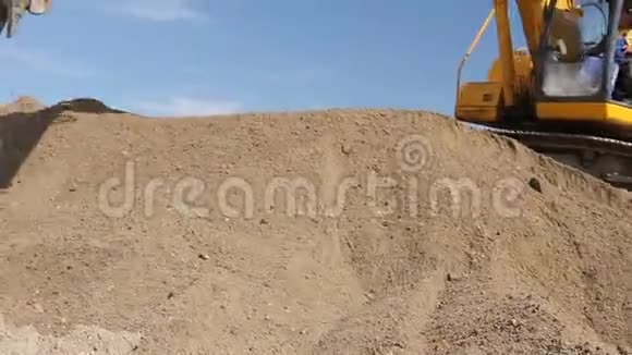 挖掘机正在准备一堆沙子以便在建筑工地的卡车上装载视频的预览图