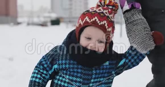 小男孩穿着冬天温暖的夹克在冬天和年轻的母亲散步视频的预览图