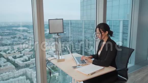 商务女性在一个位于摩天大楼高层的现代化办公室工作在笔记本电脑上工作的漂亮女孩视频的预览图