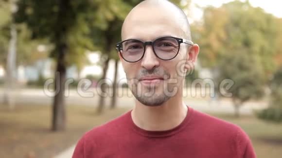 一个年轻的秃头在公园里吃三明治美味的食物快乐视频的预览图