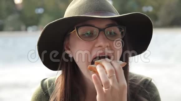 一个戴着眼镜和帽子的年轻女孩正在吃一个美味的三明治食物不好吃情感视频的预览图