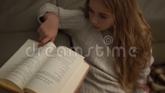 少女坐在满是格子地毯的地板上看书圣诞节灯光家庭舒适视频的预览图
