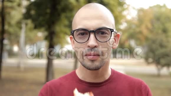 公园里的一个年轻秃头吃三明治不好吃的不好吃的三明治视频的预览图