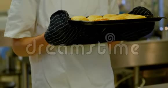 男厨师闻着厨房里的饼干托盘视频的预览图