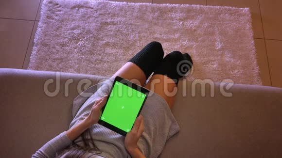年轻女性少年手持绿色屏幕平板电脑的特写镜头女生双腿穿着可爱的袜子视频的预览图