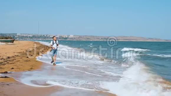 一个年轻人走在沙滩上用手机拍了一只海鸥视频的预览图