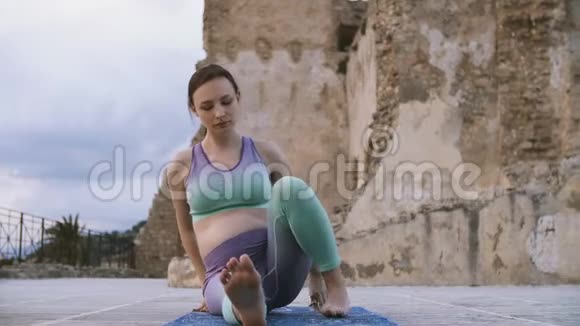 孕妇在户外做瑜伽未来的母亲坐在莲花的位置视频的预览图
