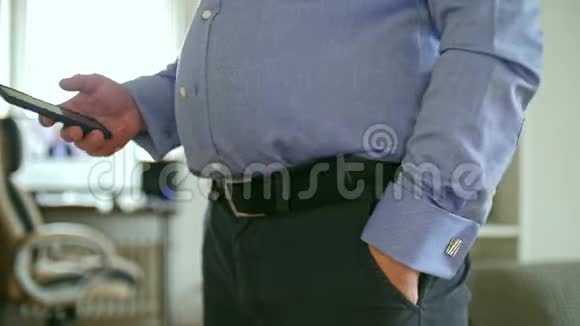 穿衬衫的胖子抚摸着他的腹部用智能手机视频的预览图