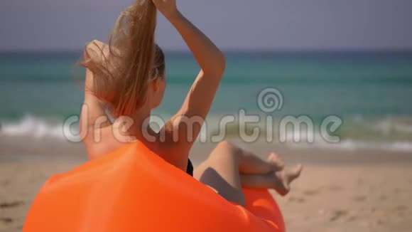 一位年轻女子在一张充气沙发上在热带海滩上放松的超慢镜头视频的预览图