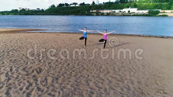 两个女人在城市河边的海滩上做瑜伽美丽的景色维里克哈萨纳姿势视频的预览图