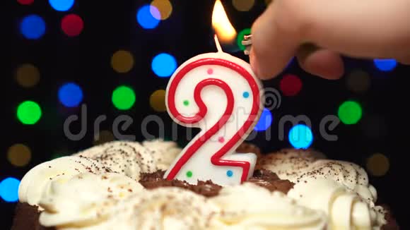 蛋糕上的2号两个生日蜡烛燃烧在最后吹灭彩色模糊背景视频的预览图