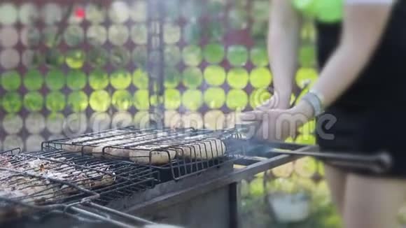 女孩用自制的香肠在烤架上用煤把烤架转动视频的预览图