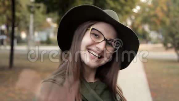 秋天公园里一个快乐的女孩叫一个朋友感情戴帽子戴眼镜的女孩视频的预览图