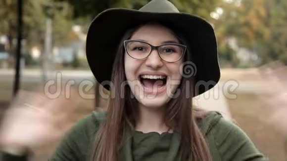 秋天公园里一个快乐的女孩感情戴帽子戴眼镜的女孩视频的预览图