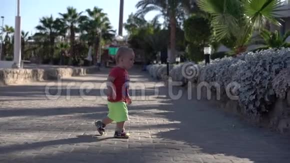 穿短裤的小男孩在海滩上慢动作地散步视频的预览图