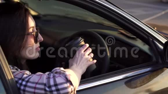 一个年轻的女人坐在车里喝咖啡慢节奏视频的预览图
