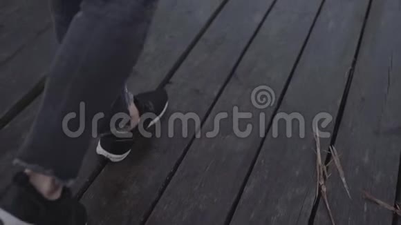 穿着运动鞋和黑裤子的女人走在潮湿的木板码头上视频的预览图