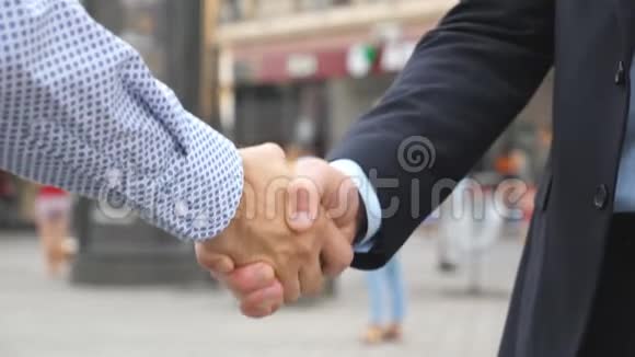 两位年轻的男性同事握手城市背景模糊城市里自信的商人互相问候视频的预览图