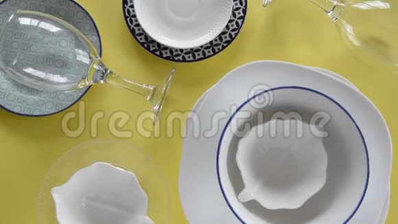 不同的瓷盘和酒杯在新鲜的黄色背景上视频的预览图