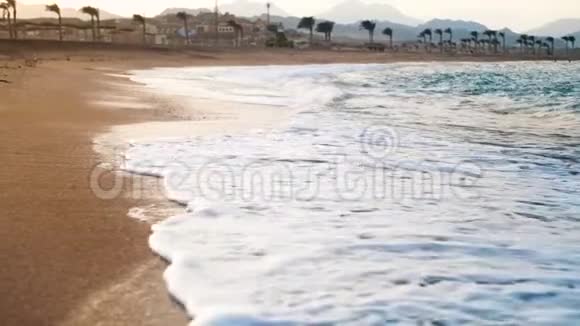 在沙滩上翻滚的海浪上拍摄的令人惊叹的日落4K镜头视频的预览图