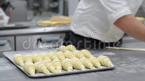 糕点厨师擀角面包面团在糕点店里放一个烤盘视频的预览图