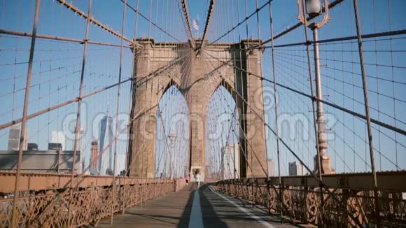 一对年轻的欧洲浪漫情侣在夏日的布鲁克林大桥上手牵着手跑向镜头视频的预览图