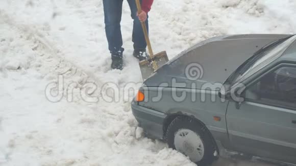 一个人从一辆被困在雪地里的车里挖了一铲雪视频的预览图