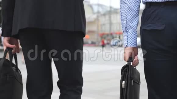 无法辨认的年轻商人带着公文包在城里散步两个自信的企业家带着行李上下班视频的预览图