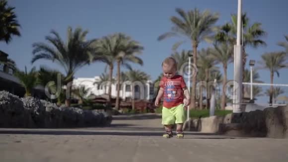 穿短裤的小男孩在海滩上慢动作地散步视频的预览图