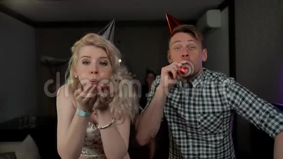一对漂亮的年轻夫妇在派对上玩吹口哨的糖果视频的预览图