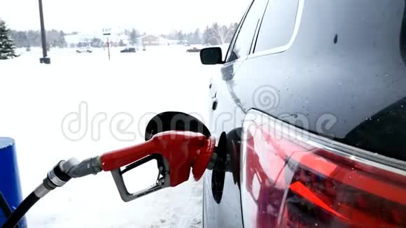 带有红色手柄的燃油喷嘴在冬季暴风雪期间为黑车加油视频的预览图