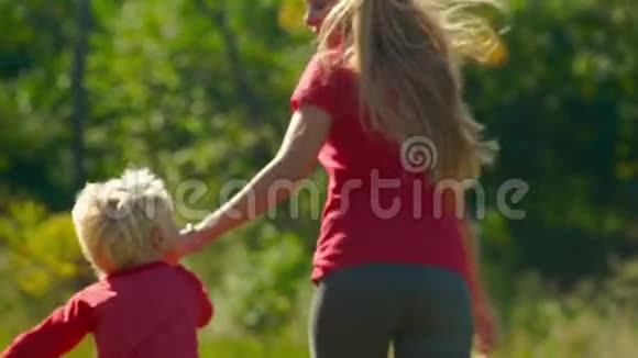 一个年轻女人和她的小儿子在草坪上玩得很开心视频的预览图